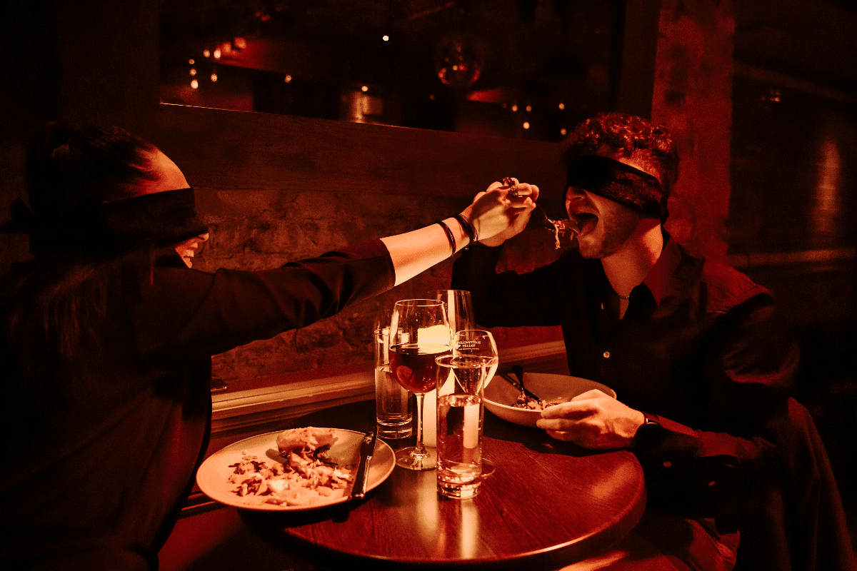 A woman feeding her partner at the Dining in the Dark experience.