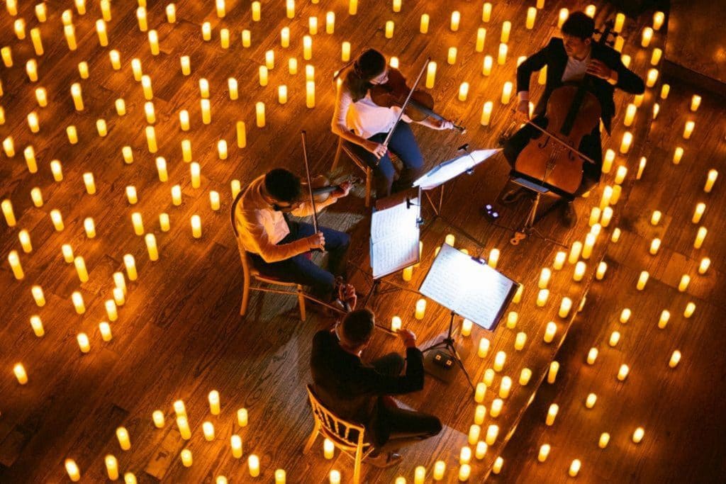 above shot of a string quartet performing on stage surrounded by hundreds of candles