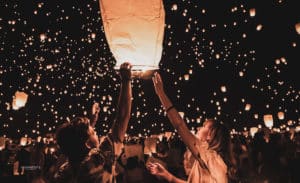 Two people release a sky lantern into the air to join thousands of other rising sky lanterns