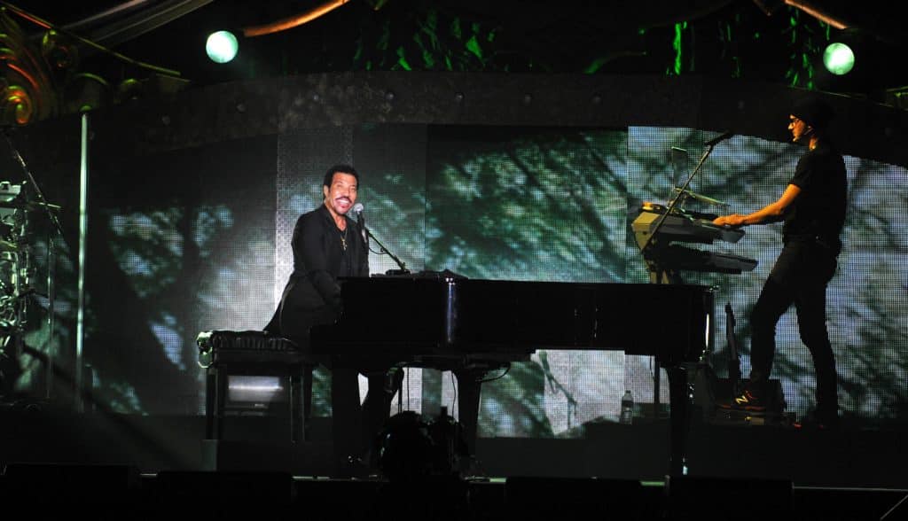 Photo of Lionel Richie singing and playing piano during a live concert