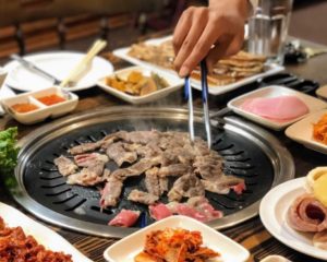 Customer cooking meat at Korean BBQ in Woo Mee Ok, Dallas